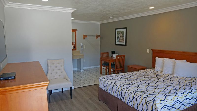 A hotel room with a bed, desk, chair, and TV