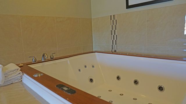 A large white jacuzzi tub with wooden accents and tiled surround