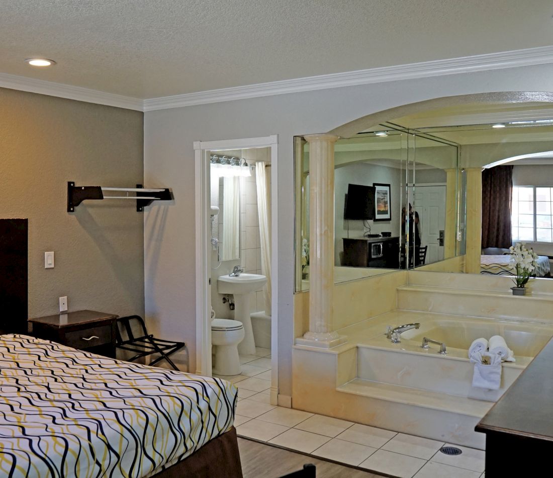 A hotel room with a jacuzzi tub, toilet, and bed