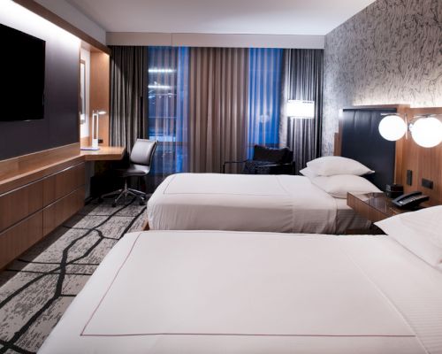 A hotel room with two beds, a desk, and a TV