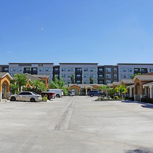 This image shows a residential area with single-story houses on either side of a wide driveway, and an apartment building in the background.