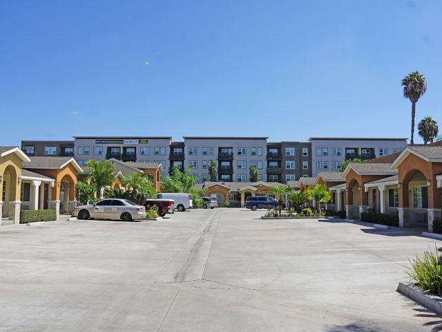 A parking lot with several cars and buildings in the background.